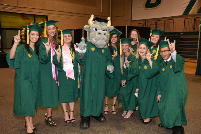 Graduating students holding up the bulls hand sign with Rocky