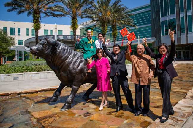 People posing on a bull in front of the marshal student center